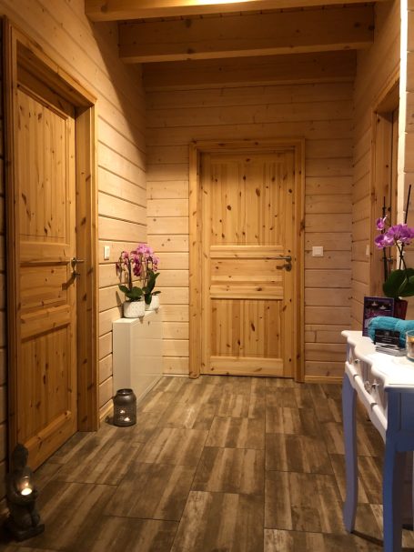 Holzvertäfelter Flur mit zwei Türen, einer Blumenvase und Holzfußboden.